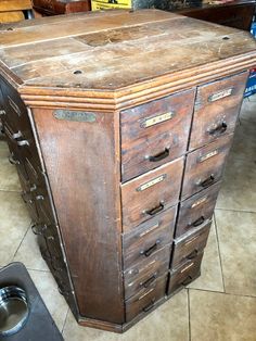 an old wooden filing cabinet sitting on top of a floor next to a trash can