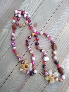 This one of a kind necklace features brown, golds and magenta beads. It also features two quartz blossoms. The necklace is handcrafted with a combination of gemstones and beads knotted by hand on pink colored cord. Necklace Length: 35 inches (drops 17.5 in) Necklace weight: 107 g (3.8 oz) Bohemian Brown Flower Necklace, Bohemian Flower Necklaces With Natural Stones, Bohemian Pink Beaded Necklace With Gemstones, Knotted Necklace, Modern Necklaces, Knot Necklace, Cord Necklace, Unique Necklaces, Boho Necklace