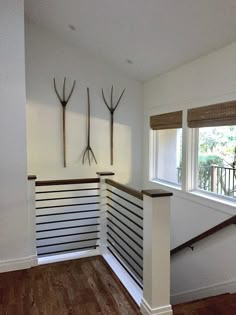 an empty room with wood flooring and white walls, two antlers on the wall