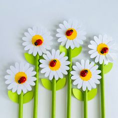 four green and white flowers with ladybugs on them are lined up against the wall