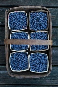 blueberries are arranged in baskets on a wooden table, ready to be eaten by someone