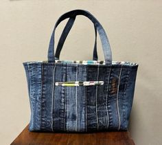 a denim tote bag sitting on top of a wooden table next to a wall