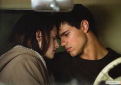 a young man and woman cuddle together in the back seat of a car while looking at each other