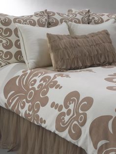 a bed with brown and white comforters on top of it's headboard