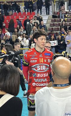 a man standing in front of a crowd wearing a red jersey