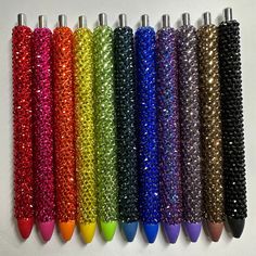 several different colored pens lined up next to each other on a white surface with lots of beads