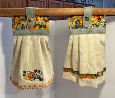 two towels hanging on a clothes line with pumpkins and leaves embroidered on the bottom