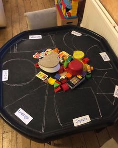 a child's play table with toys on it and writing on the blackboard