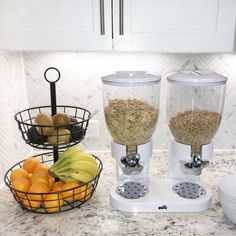 two blenders sitting on top of a counter next to bowls of fruit and cereal