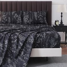 a bed with black and white comforter in a bedroom next to a night stand