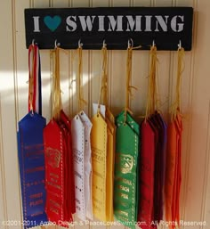 an assortment of umbrellas hanging on a wall with i love swimming sign above them