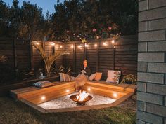 a woman sitting on a bench in the middle of a yard with lights strung around her