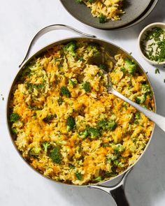 two pans filled with rice and broccoli on top of a white table