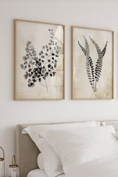 two paintings on the wall above a bed in a room with white sheets and pillows