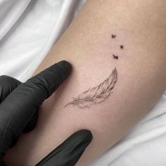 a woman's arm with a small feather and butterflies tattoo on the left thigh