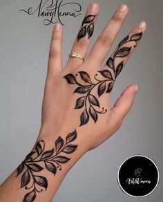 a woman's hand with tattoos on it and leaves painted on the palm area