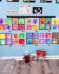 a blue wall with many hand prints on it and a red stuffed animal sitting in front of them