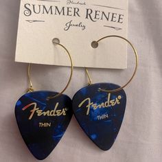 pair of blue guitar picks with the words fender's thin on them hanging from gold hoop earrings