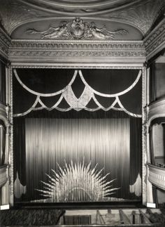 an old black and white photo of a stage with the curtain drawn back to reveal a starburst