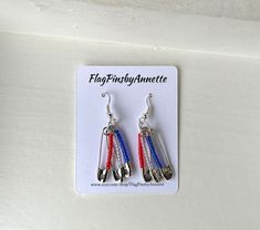 two pairs of earrings with red, white and blue ribbons hanging from the ear hooks