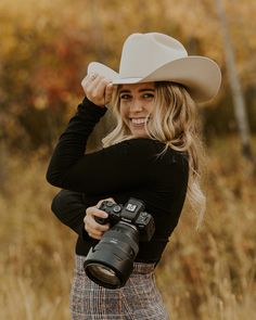 a woman wearing a cowboy hat and holding a camera in front of her face while posing for a photo