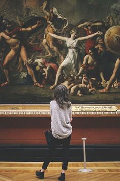 a woman standing in front of a large painting