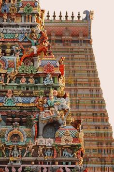 an elaborately decorated tower in front of a tall building with statues on the top