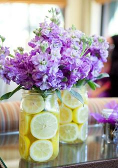 two mason jars filled with lemons and purple flowers