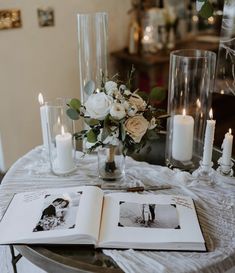 an open book on a table with candles and flowers