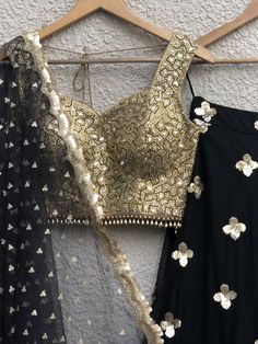 This stunning hand embellished gold mirror work blouse is teamed with a gorgeous black gold skirt with 3D sequins flower and gold border. This outfit is completed with a black scallop dupatta with scattered gold butis. Black And Gold Lehenga, Scallop Dupatta, Sequins Lehenga Choli, Sequins Lehenga, Sequin Lehenga, Black Velvet Blouse, Gold Sequin Skirt, Gold Lehenga, Mirror Work Blouse