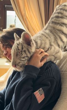 a woman holding a white tiger cub in her arms