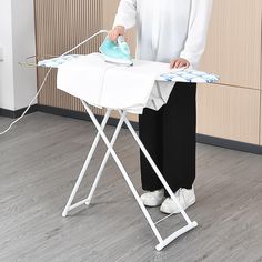 a woman ironing clothes on an ironing board