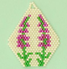 a beaded ornament with pink flowers and green leaves on a light green background