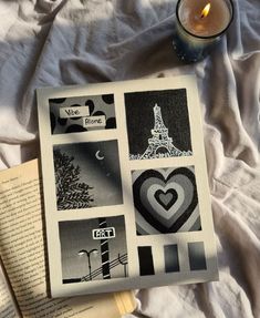 an open book sitting on top of a bed next to a candle and some pictures