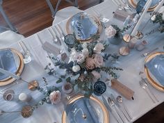 the table is set with plates, silverware and floral centerpieces on it