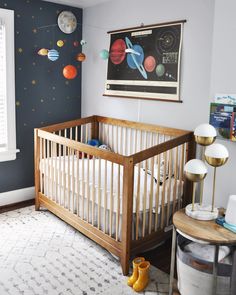 a baby's room with a crib and space themed wallpaper