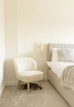 a bedroom with a bed, chair and cat sleeping on the floor next to it