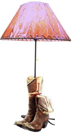 a pair of cowboy boots sitting under a pink shade on top of a floor lamp