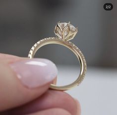 a close up of a person's hand holding a ring with a flower on it