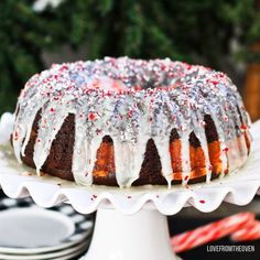 a bundt cake with white icing and sprinkles on top sitting on a plate