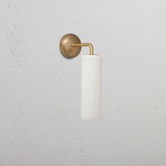 a white and gold toilet paper holder on the side of a wall with a light in it