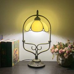 a table lamp sitting on top of a wooden table next to a vase with flowers