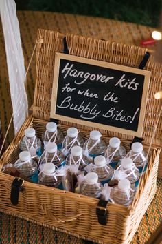 a wicker basket filled with bottles of booze next to a chalkboard sign that reads hangover kits for when the bubbly bites