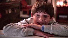 a young boy leaning on a table with his arms crossed