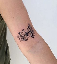 a woman's arm with a black and white butterfly tattoo on the left forearm