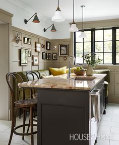 a kitchen with an island in the middle of it and pictures on the wall behind it