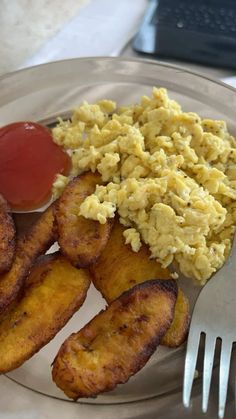 a plate with eggs, fried bananas and ketchup on it next to a fork