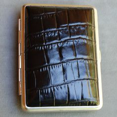 "Genuine Crocodile patent leather embossed cowhide personal case from Germany. Soft, warm and elegant to the touch. Personal case holds cards, money, 14 cigarettes. credit cards or what have you. Hand assembled in Germany by European craftsmen in old world quality. Perfect handy containers for pocket, purse or desk; each case neatly fits your personal needs or what-you-will in an elegant retro-fashion look. Nickel plated steel \"German Silver\" rims for years of continual use. H: 3 5/8\" x W: 2 Classic Rectangular Cases With Card Slots, Black Rectangular Card Holder For Formal Occasions, Formal Compact Card Holder With Coin Pocket, Formal Rectangular Card Holder With Crocodile Pattern, Formal Crocodile Pattern Rectangular Card Holder, Formal Rectangular Crocodile Pattern Card Holder, Elegant Crocodile Pattern Card Holder, Elegant Rectangular Crocodile Pattern Card Holder, Portable Rectangular Card Holder