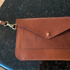 a brown leather wallet sitting on top of a counter next to a cell phone holder