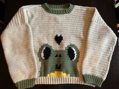 a knitted sweater with an animal on the front and green, white, and black design